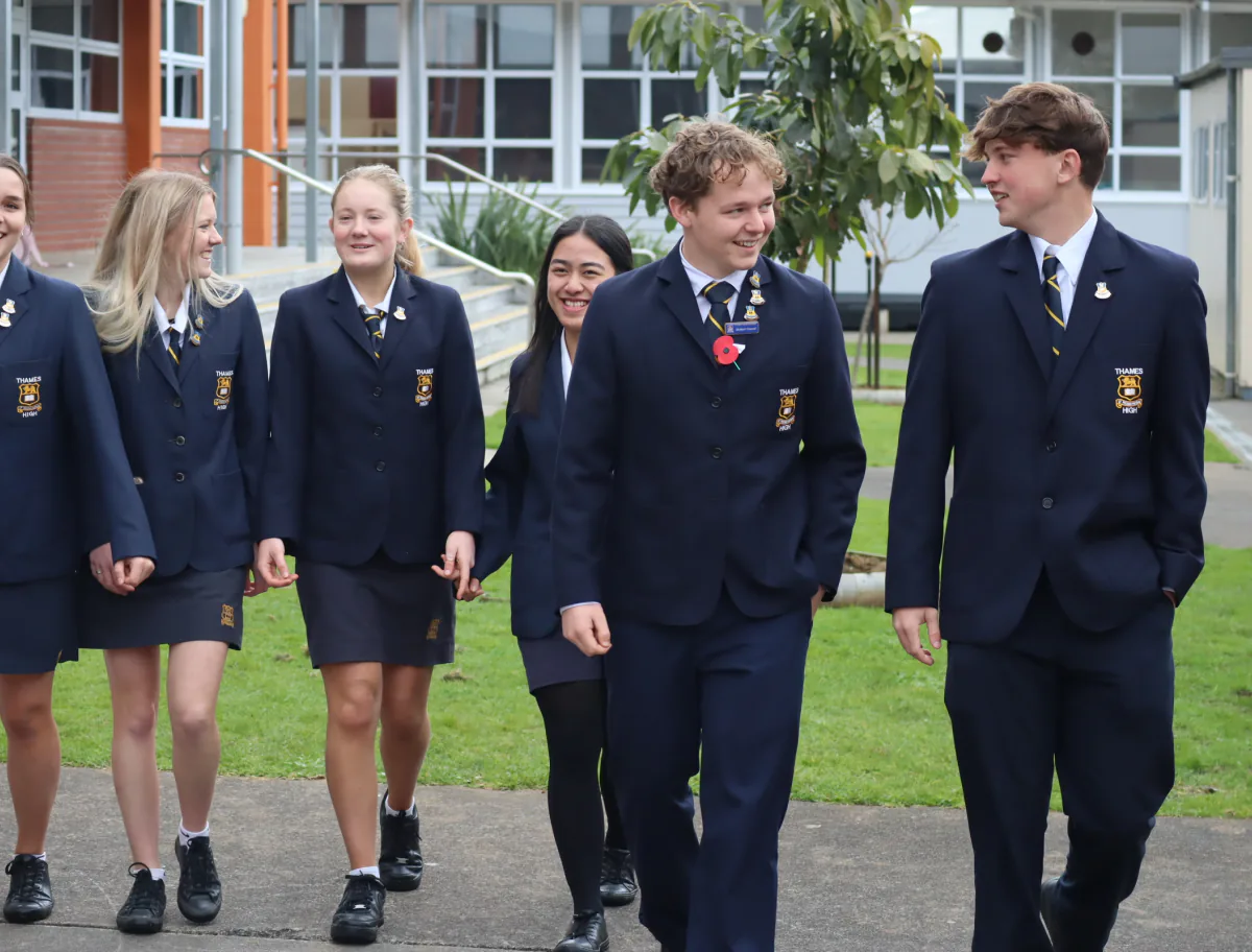 ソファに座るニュージーランド人のホストファミリーと日本人女性、および赤ちゃん。赤ちゃんは哺乳瓶を手にし、ホストマザーとホストファザーが寄り添い、家族の温かさが伝わるリビングの一場面。